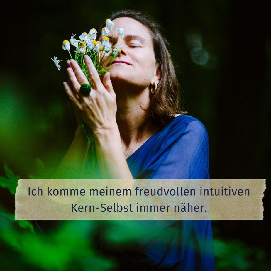 Stefanie Sauer-Bloch hält in ihren Händen einige Kamilleblüten und riecht an ihnen. Unten auf dem Bild steht: "Ich komme meinem freudvollen intuitiven Kern-Selbst immer näher."